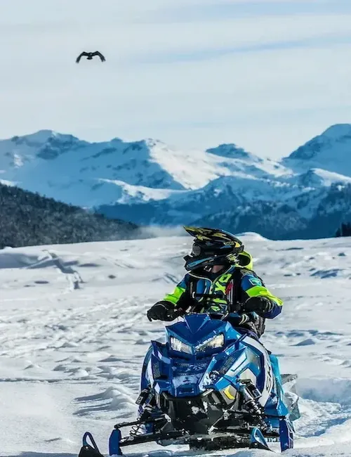 A man in the high country is seen relishing a sled ride.